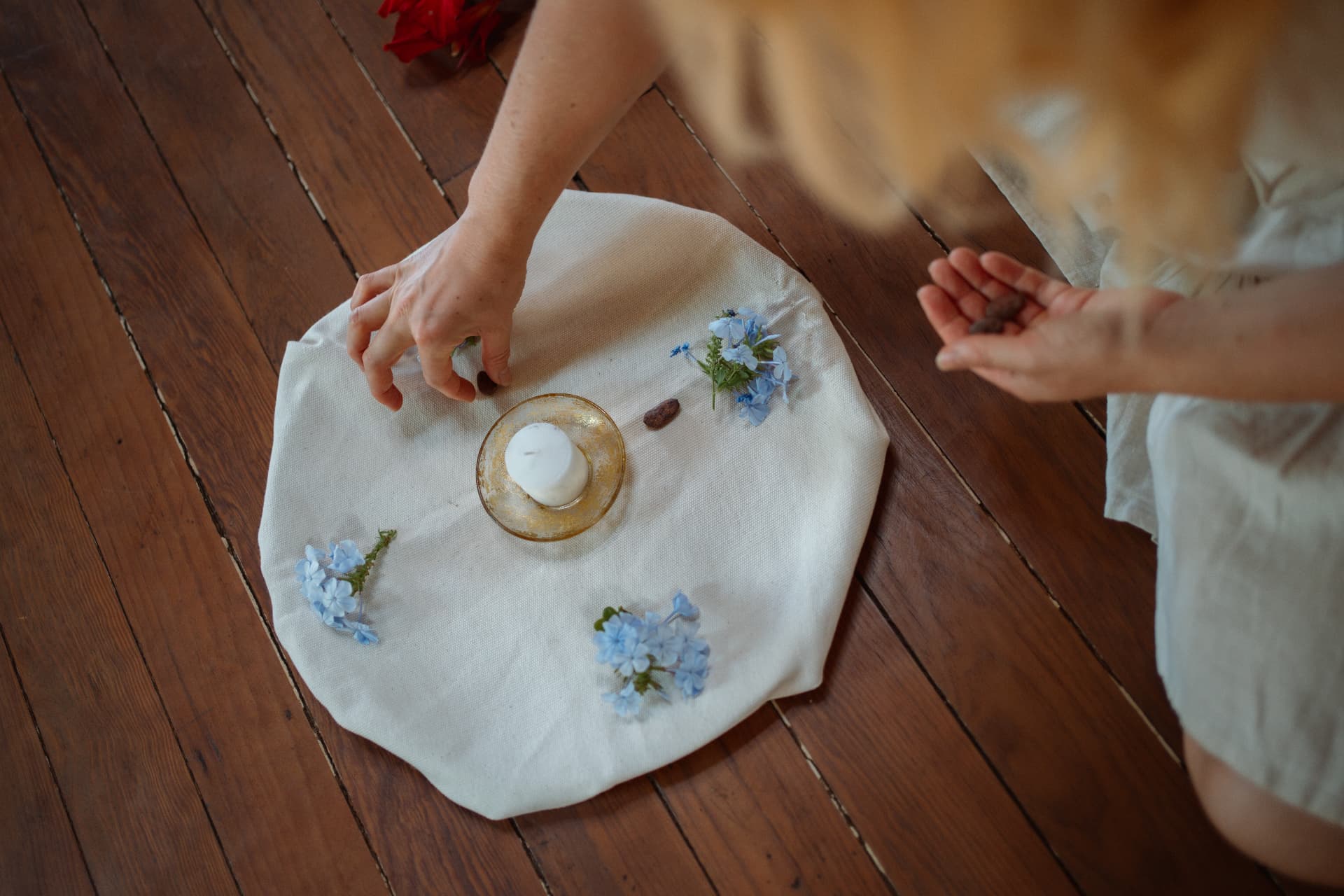 Zeremonie-Setup mit Kerze und Blüten auf einem hellen Tuch